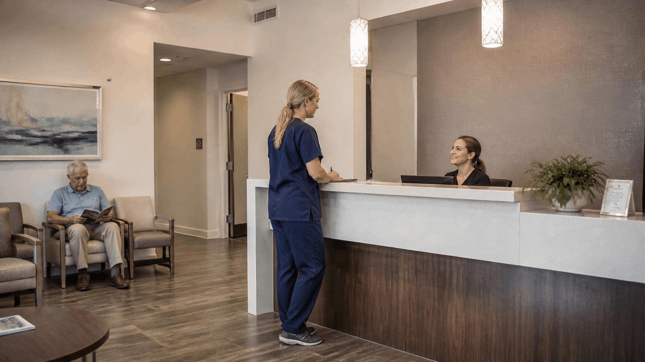 Clean and modern medical clinic reception area and waiting room with staff assisting at the front desk in Friendswood, TX